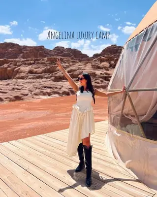 a woman in a white dress standing next to a boat at Angelina Luxury Camp in Wadi Rum