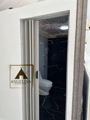 a bathroom with a toilet and a black wall at Angelina Luxury Camp in Wadi Rum
