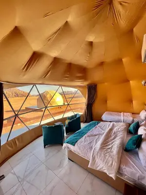 a bed in a room with a large window at Angelina Luxury Camp in Wadi Rum