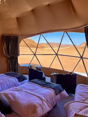 two beds in a room with a view of the desert at SARAB Luxury Camp in Wadi Rum