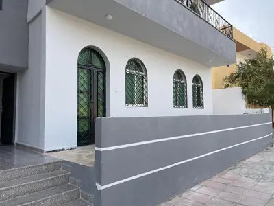 a white building with two windows and a staircase at Oskar Appartment in Wadi Musa