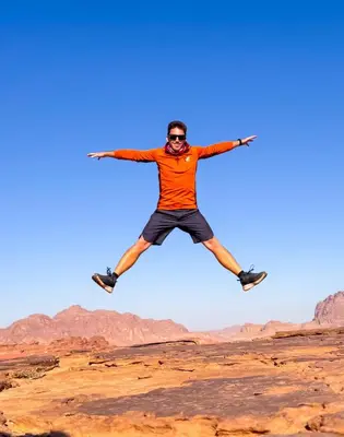 a man jumping in the air in the desert at Najd Luxury Camp in Wadi Rum