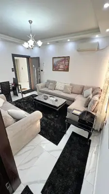 a living room with a couch and a table at شقة مفروشة بغرفتي نوم الجاردنز in Umm Uthainah