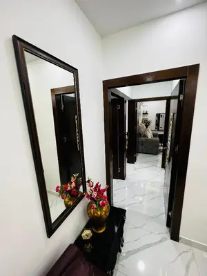 a hallway with a mirror and a table with flowers at شقة مفروشة بغرفتي نوم الجاردنز in Umm Uthainah