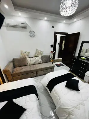 a living room with a bed and a couch at شقة مفروشة بغرفتي نوم الجاردنز in Umm Uthainah
