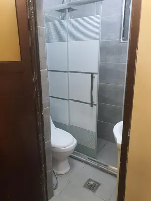 a bathroom with a toilet and a glass shower stall at Alfares Hotel in At-Tafilah