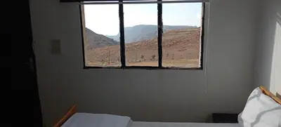 a bedroom with a window with a mountain view at Alnwatif Gate guest house Dana nature reserve in Dana