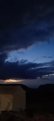 a cloudy sky at night with a building in the foreground at Alnwatif Gate guest house Dana nature reserve in Dana