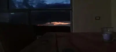 a table in a room with a window with a sunset at Alnwatif Gate guest house Dana nature reserve in Dana