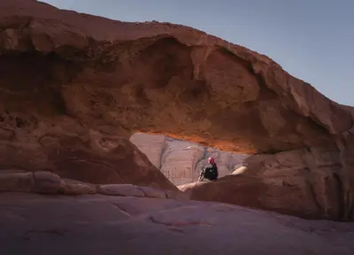 a person standing in a cave in a canyon at Wadi Rum Desert Dunes Luxury Camp in Wadi Rum