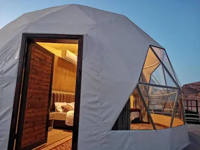 a dome tent with a bedroom in the background at Charlotte luxury camp in Wadi Rum