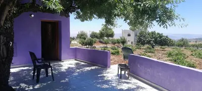 a purple house with a table and chairs under a tree at Jerash mountain studio chalet شاليه جبال جرش و عجلون in Jerash