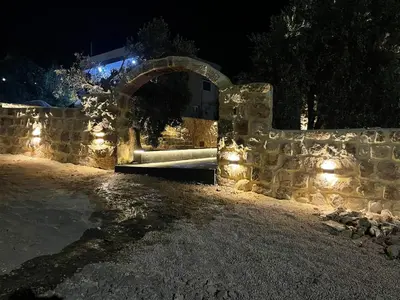 a stone wall with a bench with lights at night at Wadi Al-Nakhil Hostel in Al Khuraybah
