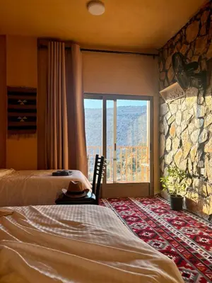 a bedroom with two beds and a large window at Wild Dana Eco Lodge- Hotel-Eco-Camp in Dana