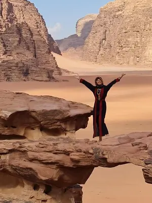 a woman standing on a rock in the desert at Tamim Luxury wadi rum camp in Wadi Rum