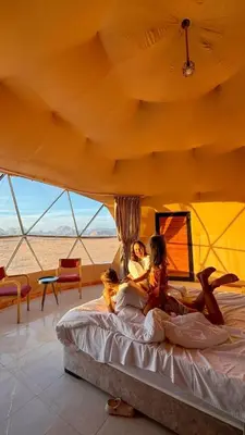two women laying on a bed in a tent at SELEN RUM LUXURY CAMP & Jeep Tours in Wadi Rum