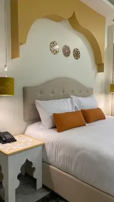 a bedroom with a bed and a table with a phone at Amman Trail Hotel & Studios in Amman