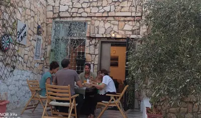 a group of people sitting at a table in front of a building at Seleucia DaR Umm Qais in Um Qeis