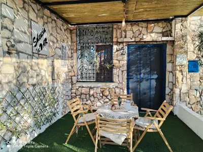 a table and chairs in front of a stone wall at Seleucia DaR Umm Qais in Um Qeis