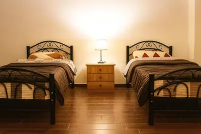 a bedroom with two beds and a lamp on a night stand at EMILE ALTWAL Hotel in Madaba