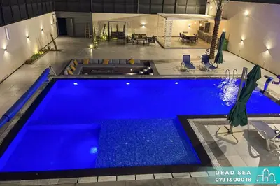 a swimming pool with blue water in a house at PYRAMID Chalets - شاليهات الهرم in Al Baḩḩāth