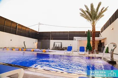 a swimming pool with a palm tree and blue chairs at PYRAMID Chalets - شاليهات الهرم in Al Baḩḩāth