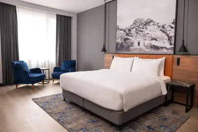 a bedroom with a large white bed and blue chairs at Radisson Blu Hotel, Amman Galleria Mall in Amman