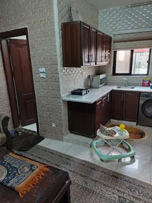 a kitchen with wooden cabinets and a table in it at شقة ام نوارة الحديثة modern nice flat in Amman