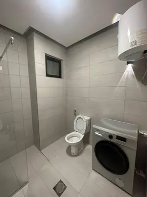 a bathroom with a toilet and a washing machine at cozy home near all services 20 in Rujm ash Sharāʼirah