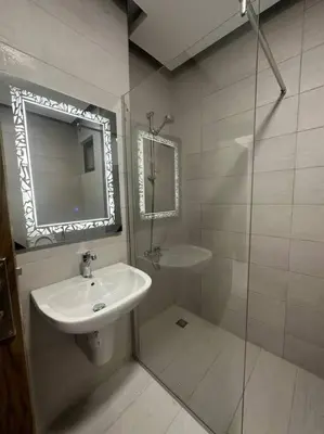 a white bathroom with a sink and a mirror at cozy home near all services 20 in Rujm ash Sharāʼirah