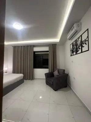 a bedroom with a bed and a chair in a room at cozy home near all services (21) in Rujm ash Sharāʼirah