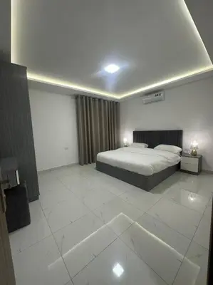 a large bedroom with a bed and a white tile floor at cozy home near all services (22) in Rujm ash Sharāʼirah