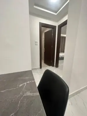 a black chair in a room with a bedroom at cozy rooftop near al services 24 in Rujm ash Sharāʼirah