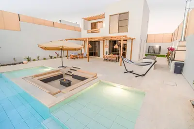 a house with a swimming pool and an umbrella at Nammos Experience in Amman