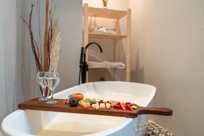 a bath tub with a wooden shelf next to a glass at Nammos Experience in Amman