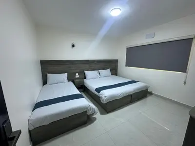 a bedroom with two beds and a flat screen tv at Happy Beach Castel for Apartment قلعة شاطئ السعادة للشقق المفروشة in Aqaba