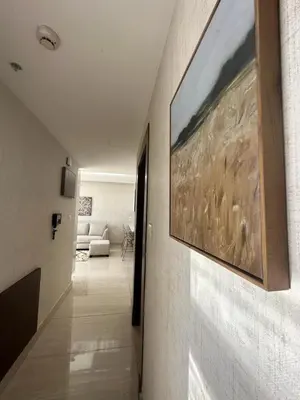 a hallway leading to a living room with a painting on the wall at Abdoun luxurious apartment in Amman