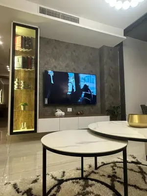 a living room with two tables and a flat screen tv at Abdoun luxurious apartment in Amman