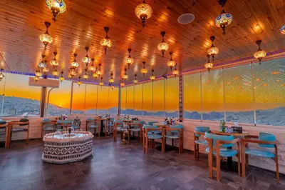 a dining room with tables and chairs and lights at Petra Bermudez Hotel in Wadi Musa