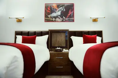 two beds in a hotel room with red and white pillows at Petra Bermudez Hotel in Wadi Musa