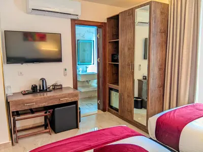 a bedroom with a desk and a tv and a bed at Petra Bermudez Hotel in Wadi Musa
