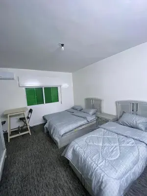 a bedroom with two beds and a desk and two windows at شقه مفروشه مميزه in Irbid
