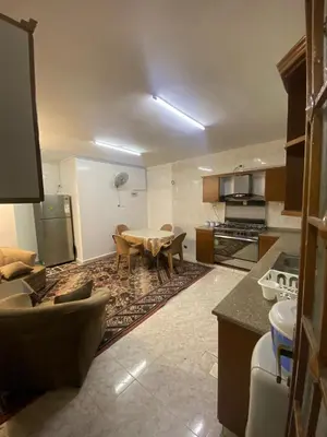 a living room with a table and a kitchen at شقه مفروشه مميزه in Irbid