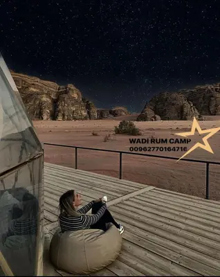 a woman sitting on a bench under the stars in the desert at Wadi rum camp in Wadi Rum