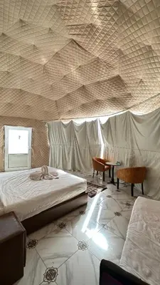 a bedroom with two beds and a table and a ceiling at Wadi rum camp in Wadi Rum