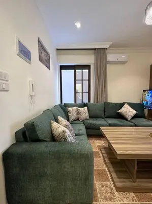 a living room with a green couch and a table at 1/ Antica jabalal-lwebdeh in Amman