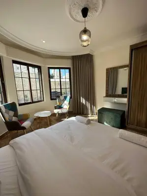 a bedroom with a white bed and a living room at 1/ Antica jabalal-lwebdeh in Amman