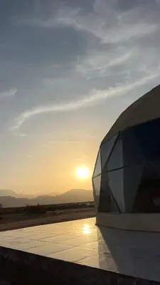a view of a building with the sunset in the background at Madonna Rum camp bubbles & Jeep tours in Wadi Rum