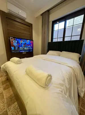 a bedroom with a large white bed with a flat screen tv at 2/ Antica jabalal-lwebdeh in Amman