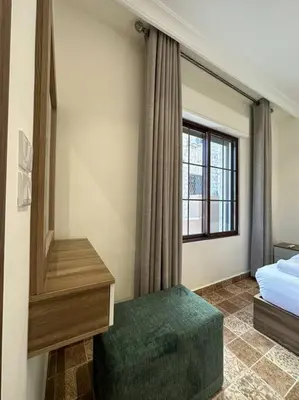 a bedroom with a bed and a window and a green ottoman at 4/ Antica jabalal-lwebdeh in Amman